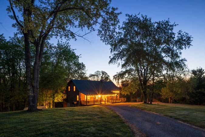 Green Acres Lodge exterior twilight view with wraparound porch lighting