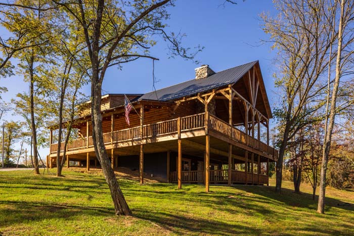 Highland Lodge log cabin exterior with wraparound deck and American flag