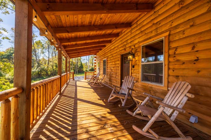 Sunlit covered log porch with rocking chairs