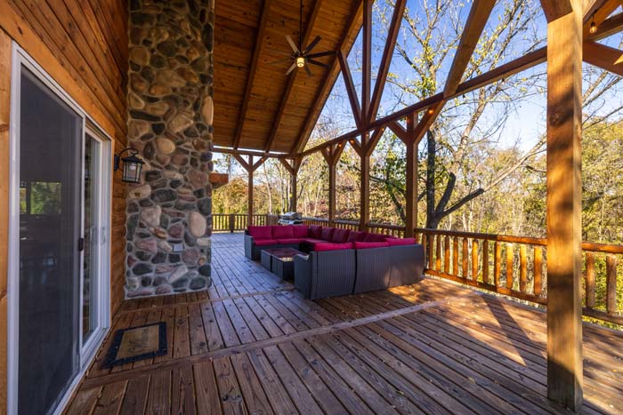 Covered deck with stone fireplace and red sectional