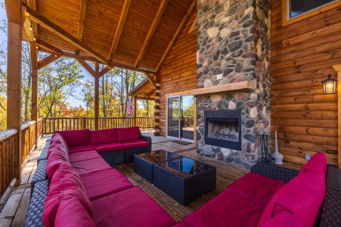Covered deck with lit gas fireplace and red sectional