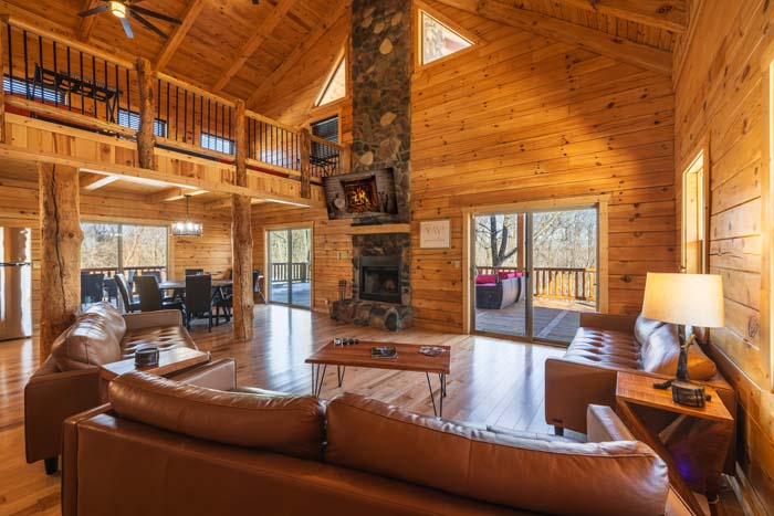 Great room with vaulted ceiling, stone fireplace, and leather sofas