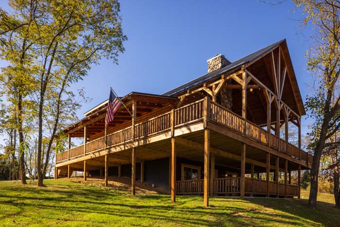 Highland Lodge log exterior with wraparound deck and stone chimney