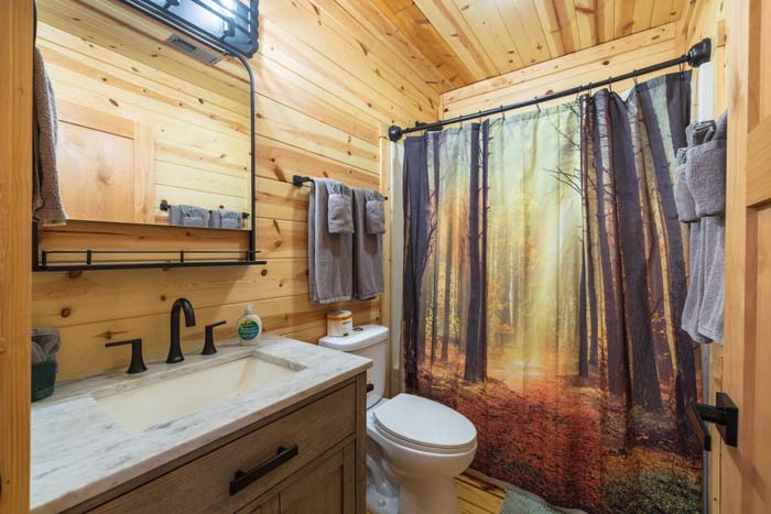 Bathroom with forest-print shower curtain and marble vanity