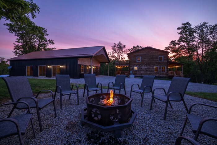 Fire pit glowing at dusk overlooking the property