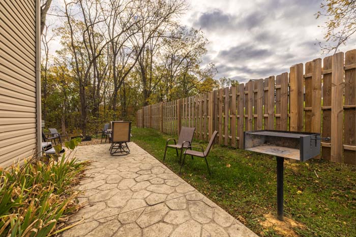 Stamped-concrete patio with charcoal grill and chairs