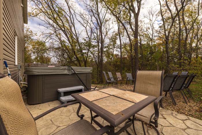 Patio with hot tub and dining table by the woods