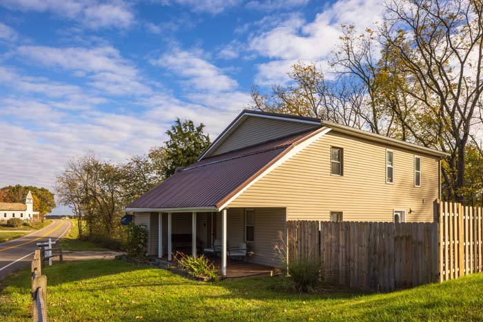 Side exterior of Hiker's Hideout with country road and distant barn