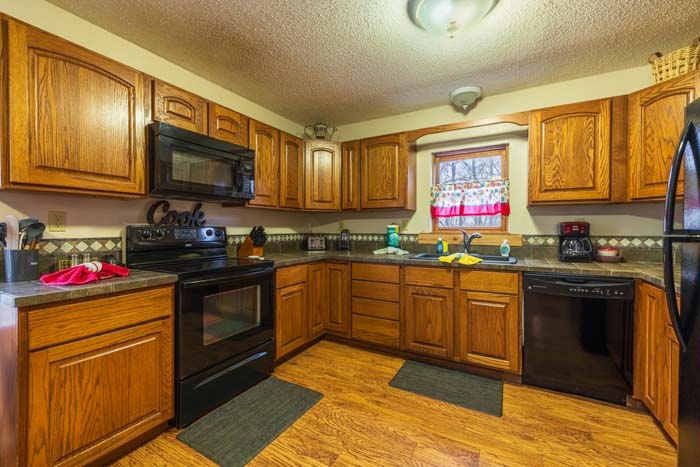 Kitchen with oak cabinets, black appliances, and tile counters