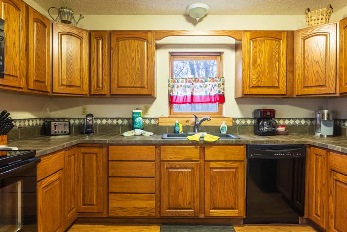 Kitchen sink beneath the window with oak cabinets