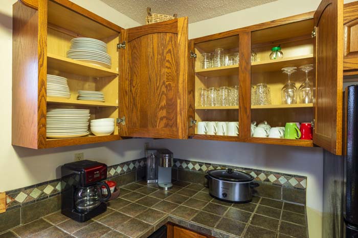 Open cabinets with dishes, glassware, and coffee makers