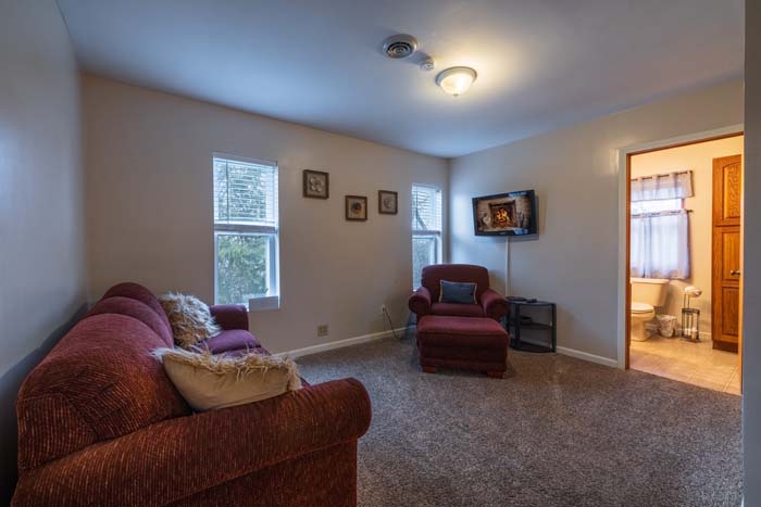 Sitting room with red sofa, chaise, and ensuite bath