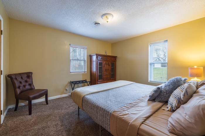 Bedroom with king bed, armoire, and leather chair