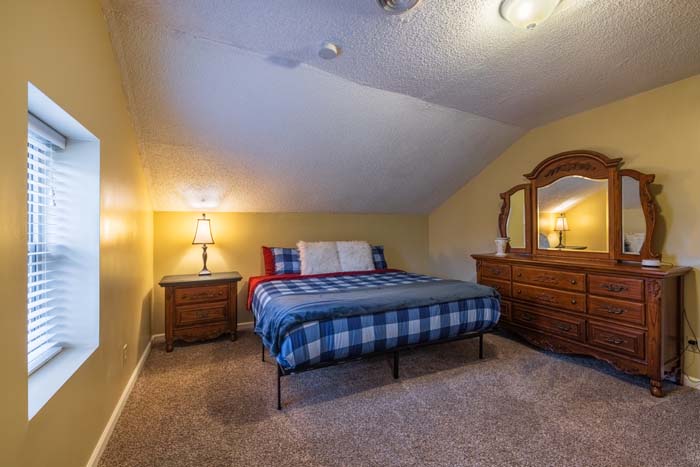 Attic bedroom with king bed and dresser in plaid bedding