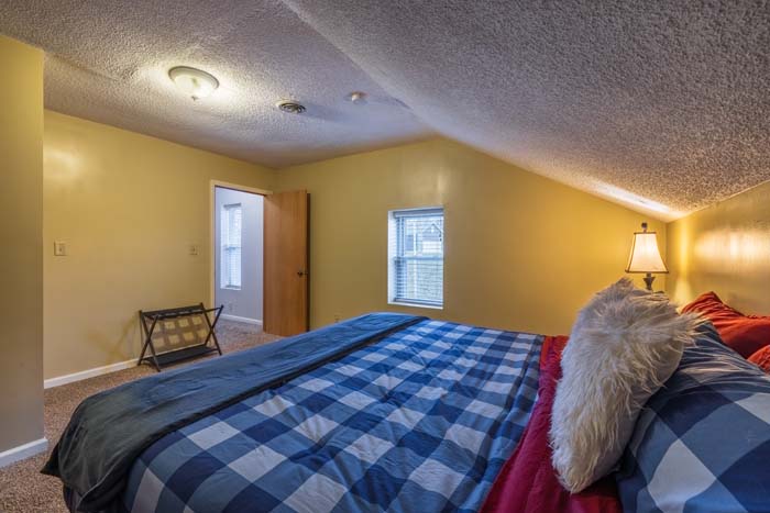Attic bedroom with king plaid bed and sloped ceiling