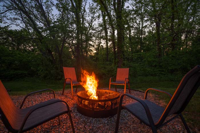 Fire pit blazing at dusk in the woods