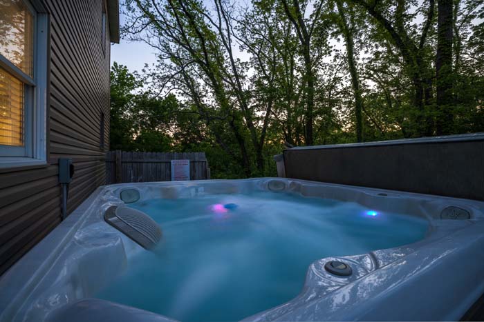 Hot tub glowing at dusk beside the house