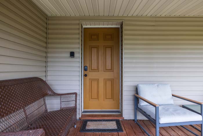 Covered front porch with wood door and seating
