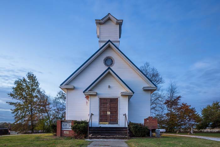 Evening view of Dragonfly Inn illuminated exterior in wooded setting