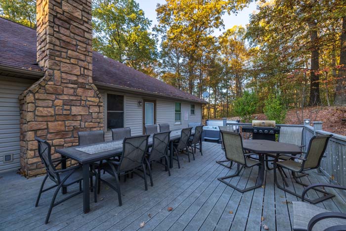 Deck dining area with stone fireplace and grill at Peach Tree Lodge