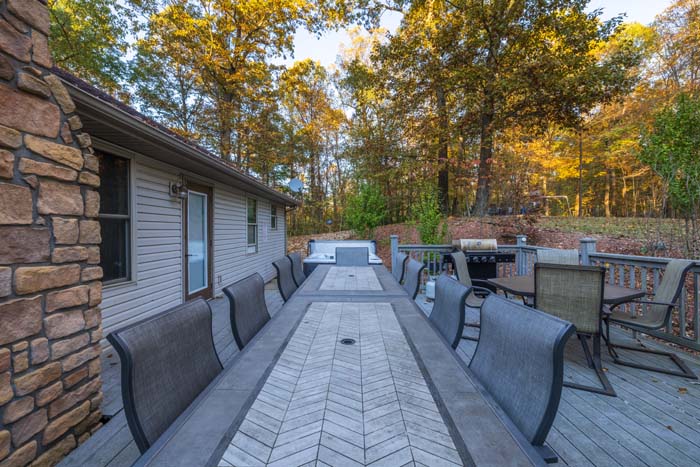 Spacious deck with dining table, hot tub, and grill at Peach Tree Lodge