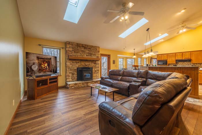 Open-concept great room with stone fireplace and leather sectional