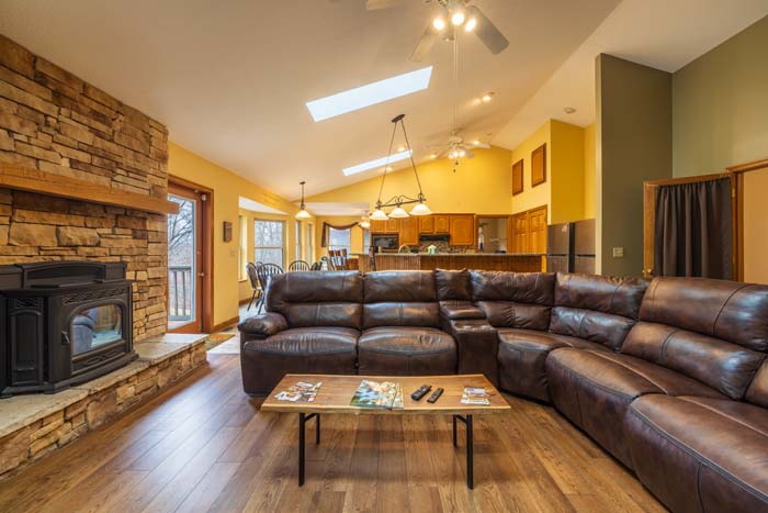 Great room with vaulted ceiling, skylights, and stone fireplace