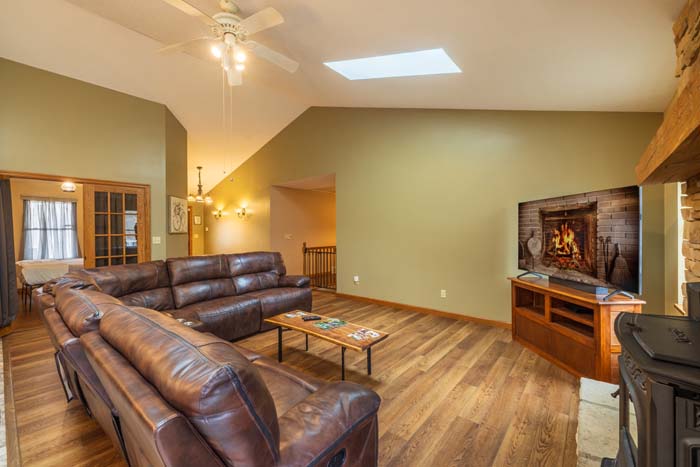 Living room with sectional, TV, and wood-burning fireplace