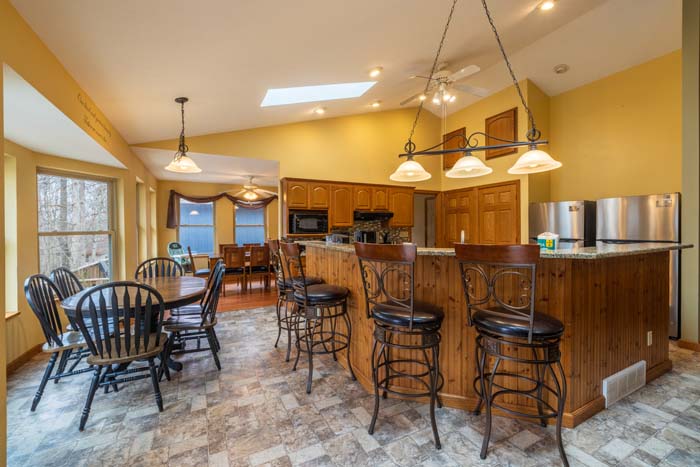 Open kitchen and dining area with bar seating and skylights