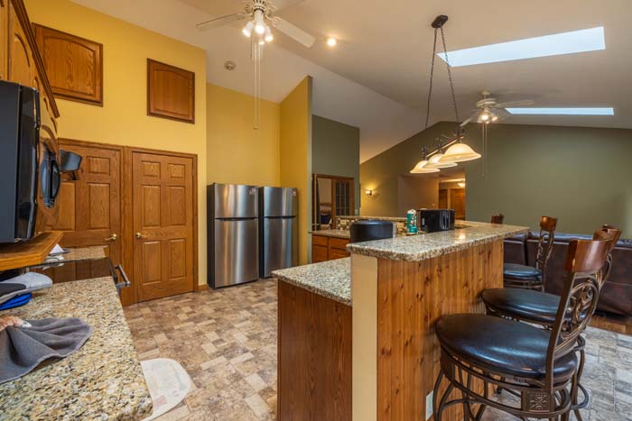 Kitchen with granite island, bar stools, and stainless refrigerator