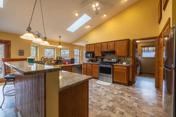 Kitchen island with granite counters and range under skylights