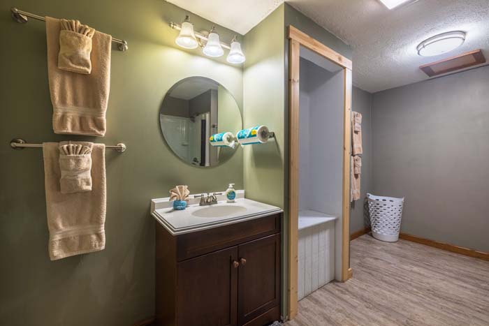 Bathroom vanity with round mirror and walk-in shower area