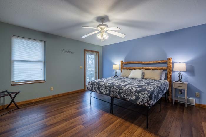 King bedroom with floral bedding and wood floors