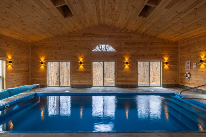 Indoor pool with arched window and wood ceiling