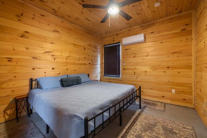 King bedroom with wood-paneled walls and mini-split heat and air