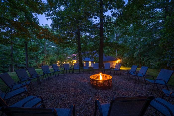 Fire pit with circle of chairs at dusk, lodge behind