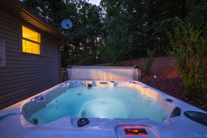 Private hot tub glowing at dusk beside Peach Tree Lodge
