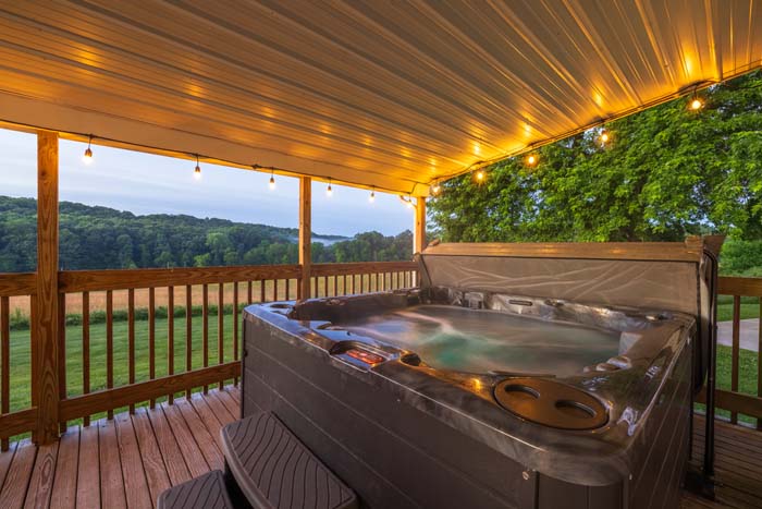 Hot tub at twilight with countryside views and string lights