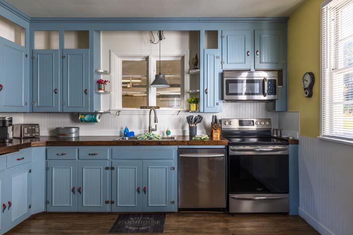 Blue kitchen cabinets with microwave, range, and dishwasher