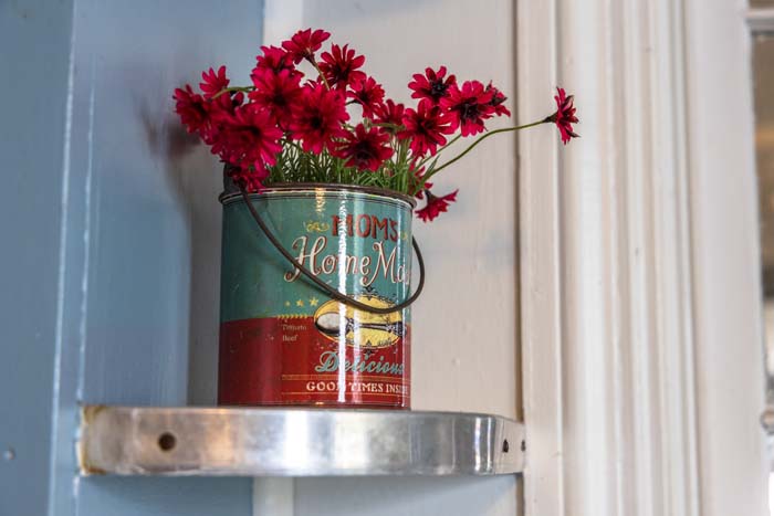 Fresh flowers in a vintage tin on a shelf