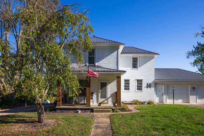 Ruby's Farmhouse front exterior framed by a shade tree