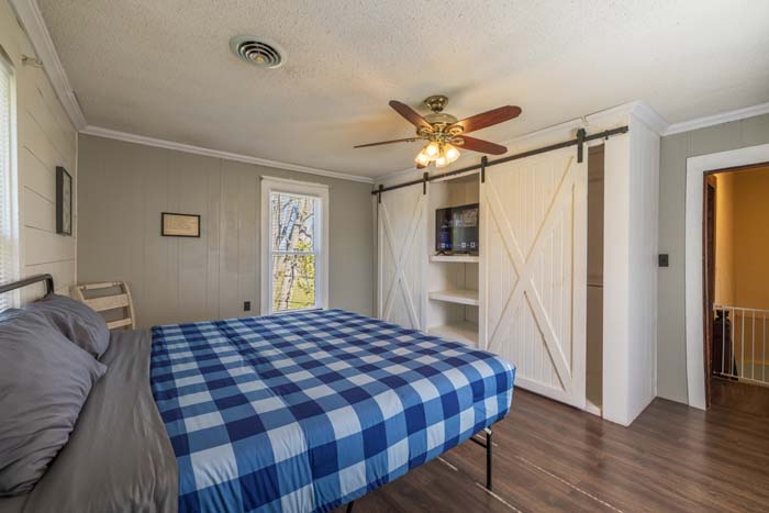 Bedroom with blue plaid bed and barn-door closet