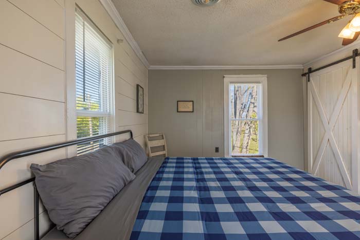 Bedroom with blue check bedding and sliding barn door