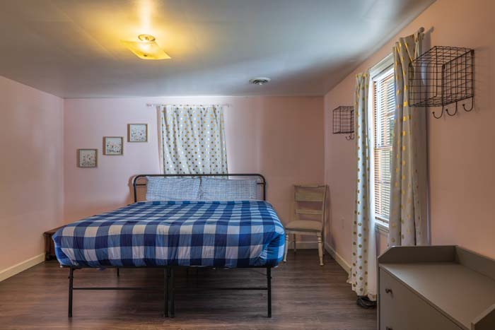 Pink bedroom with blue plaid bed and gold-dot curtains