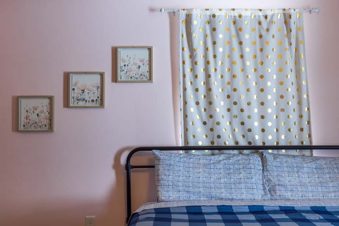 Pink bedroom with floral art and gold-dot curtain