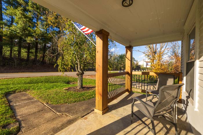 Covered porch with railing overlooking the lawn