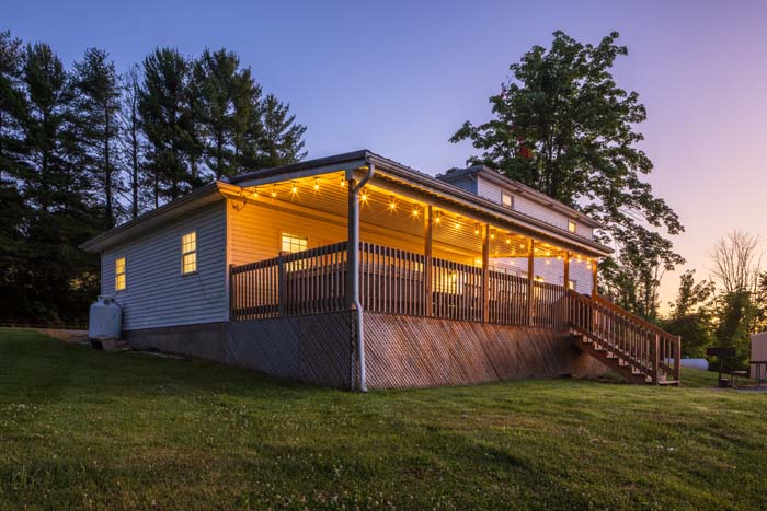 Side exterior with covered deck lit at dusk