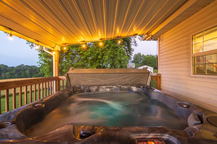 Private hot tub glowing at dusk on the covered deck