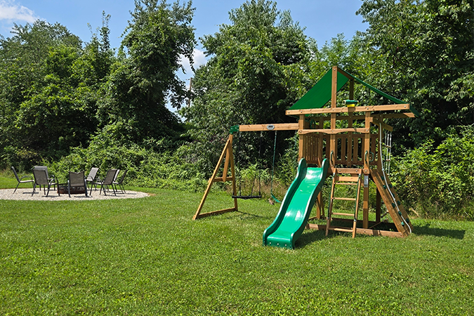 Outdoor wooden swing set with slide and patio seating in the yard at The Grange in Hocking Hills Ohio