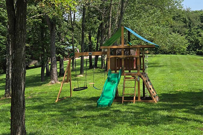 Outdoor wooden swing set with slide in the yard at Highland Lodge in Hocking Hills Ohio